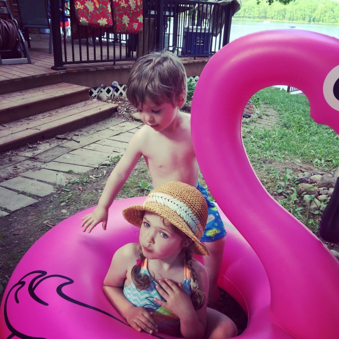 Eli and Eva sitting on a flamingo pool float.