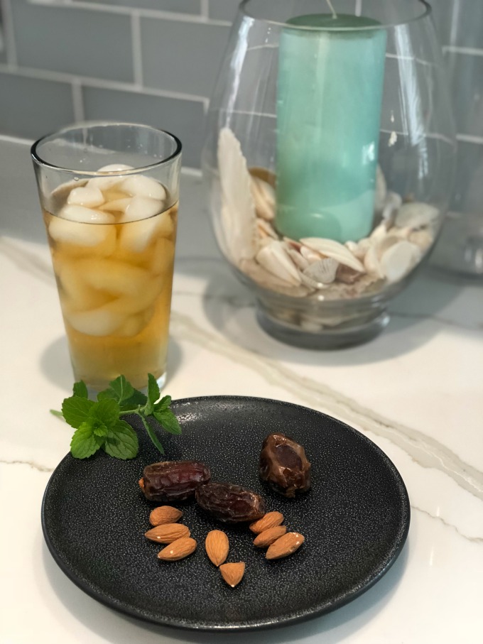 Dates an Almonds on a plate next to a drink