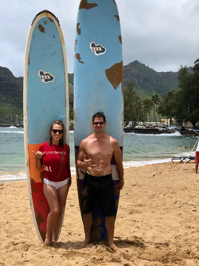 Jessica and Kyle standing by surfboards