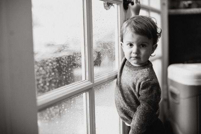 young boy standing by a window in black and white