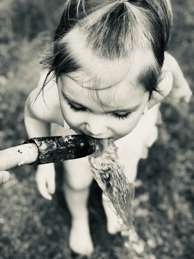 girl drinking from hose