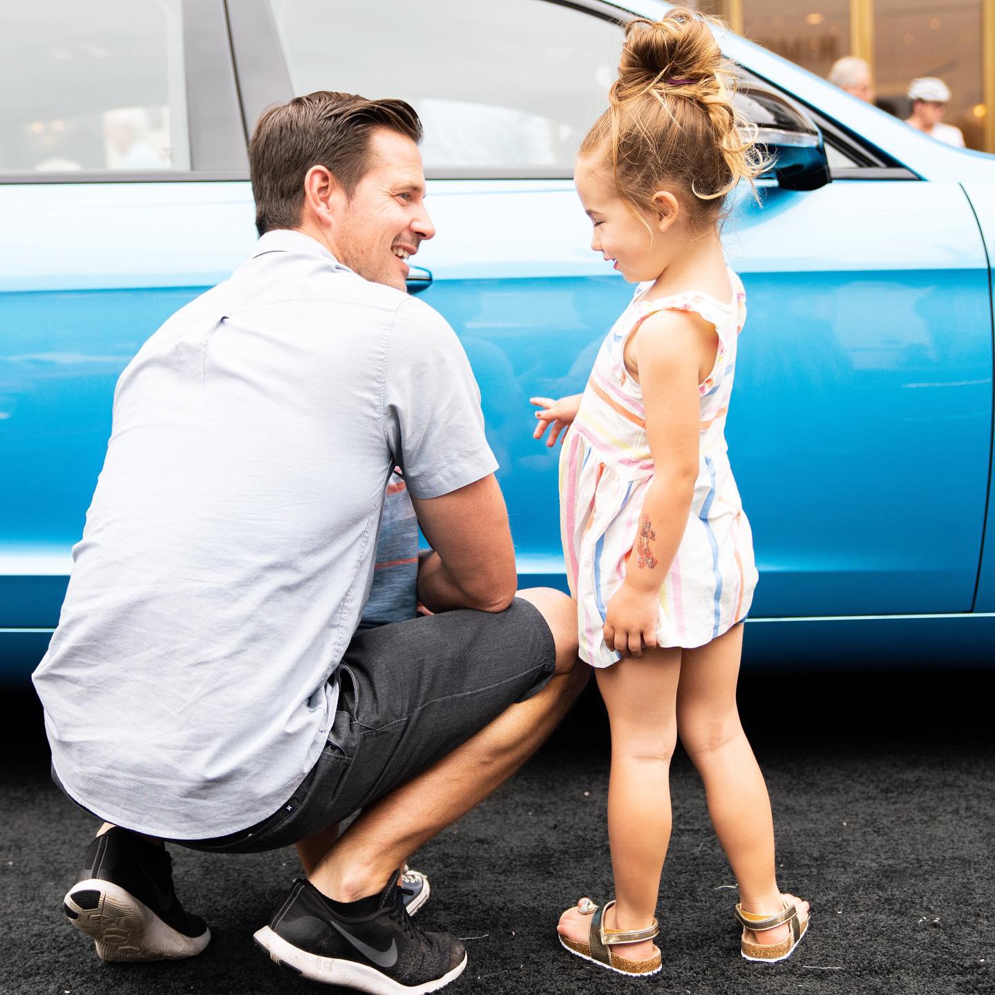 Dad and daughter standing by car.