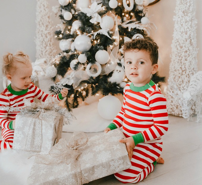 kids holding presents by christmas tree