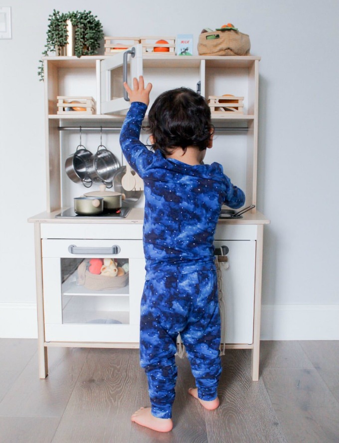 Kid with Lovey&Grink pajamas playing with kitchen