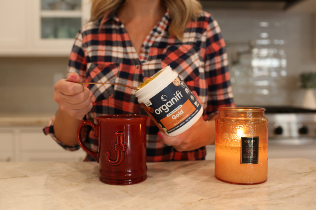 woman with pumpkin spice drink and candle