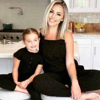 Jessica Hall and daughter wearing matching black jumpsuits.