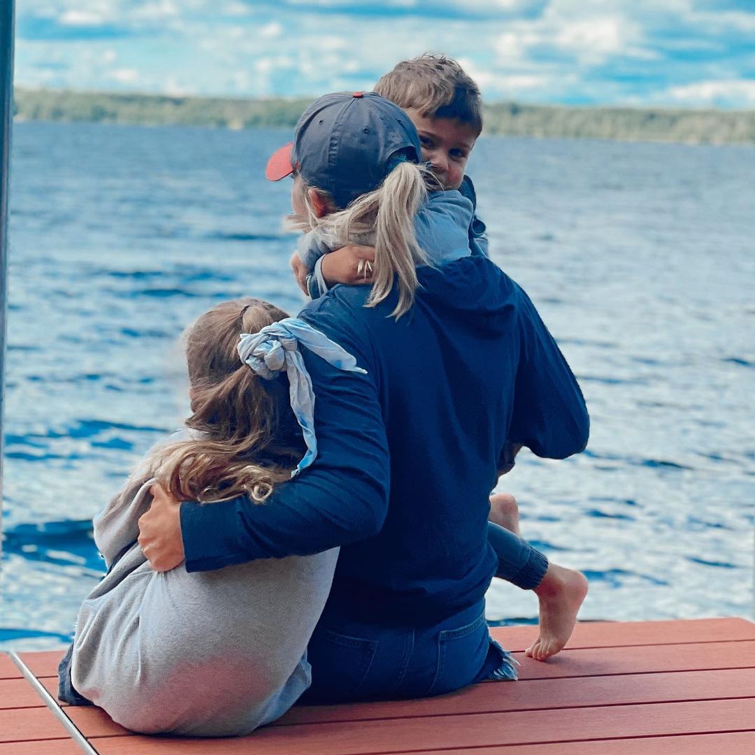 Jessica Hall and kids sitting on a dock looking out at a lake. 