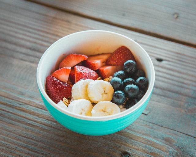 Teal bowl with strawberries, blueberries, and bananas.