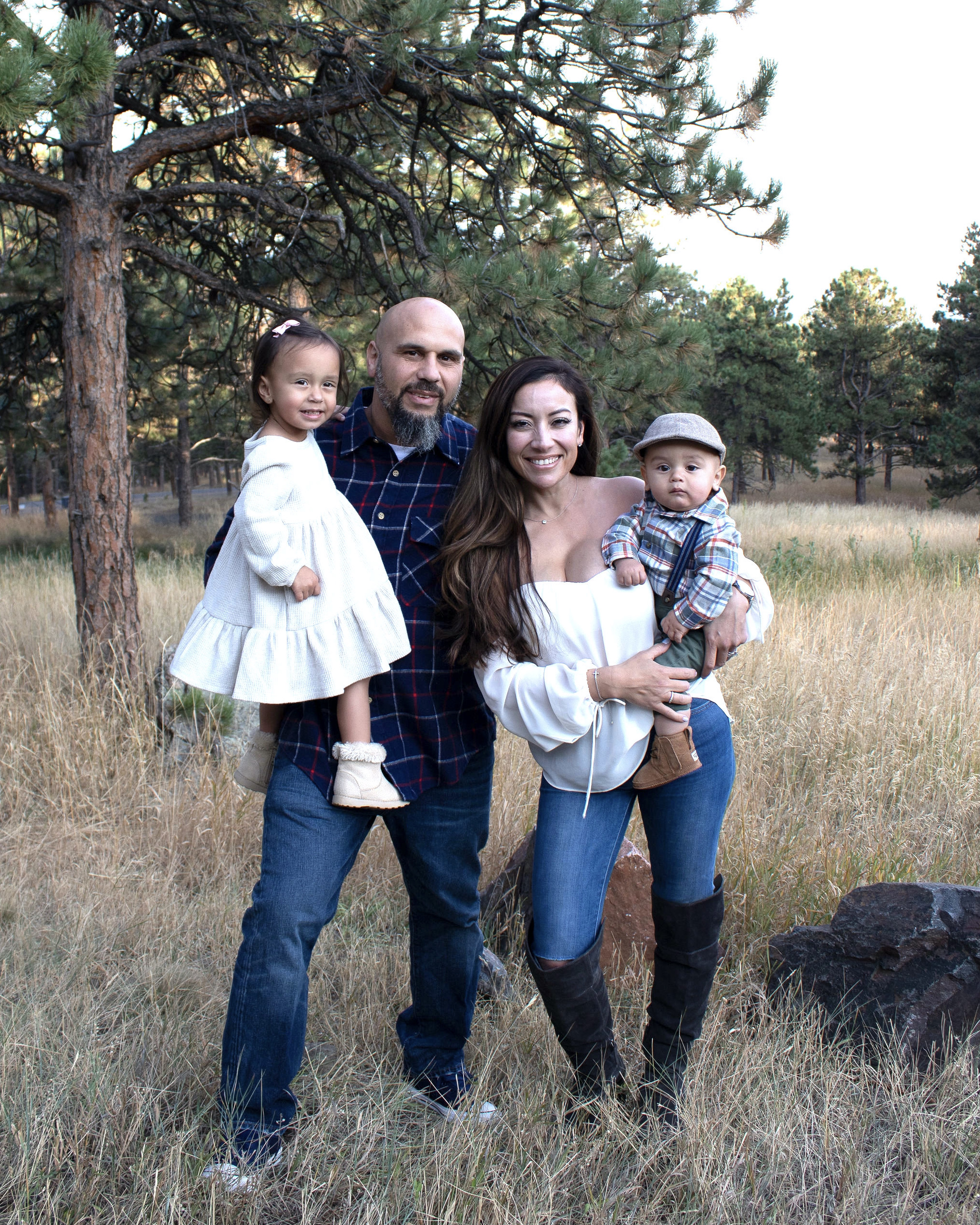 Denise and her family standing in a field in front of a tree.