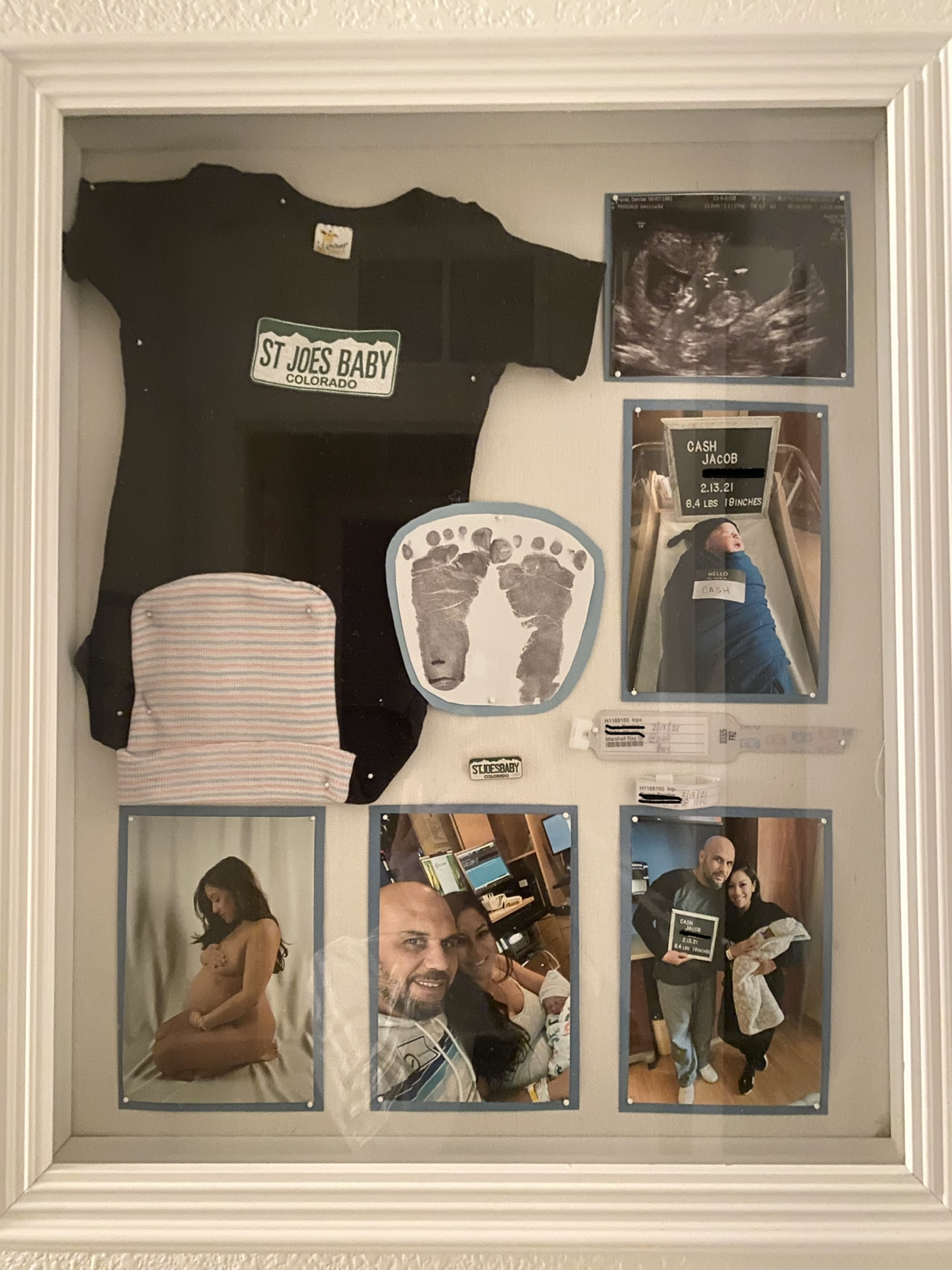 Shadow box with pictures, onesie, and other baby momentos.