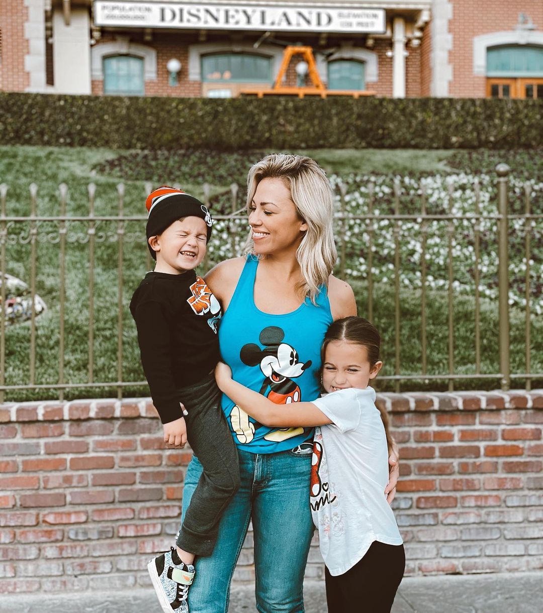 Jessica Hall wearing a shirt with Mickey Mouse standing in front of Disneyland with her kids.