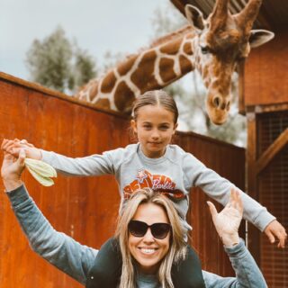 Jessica Hall with daughter sophie on her shoulders and a giraffe peaking over from behind.