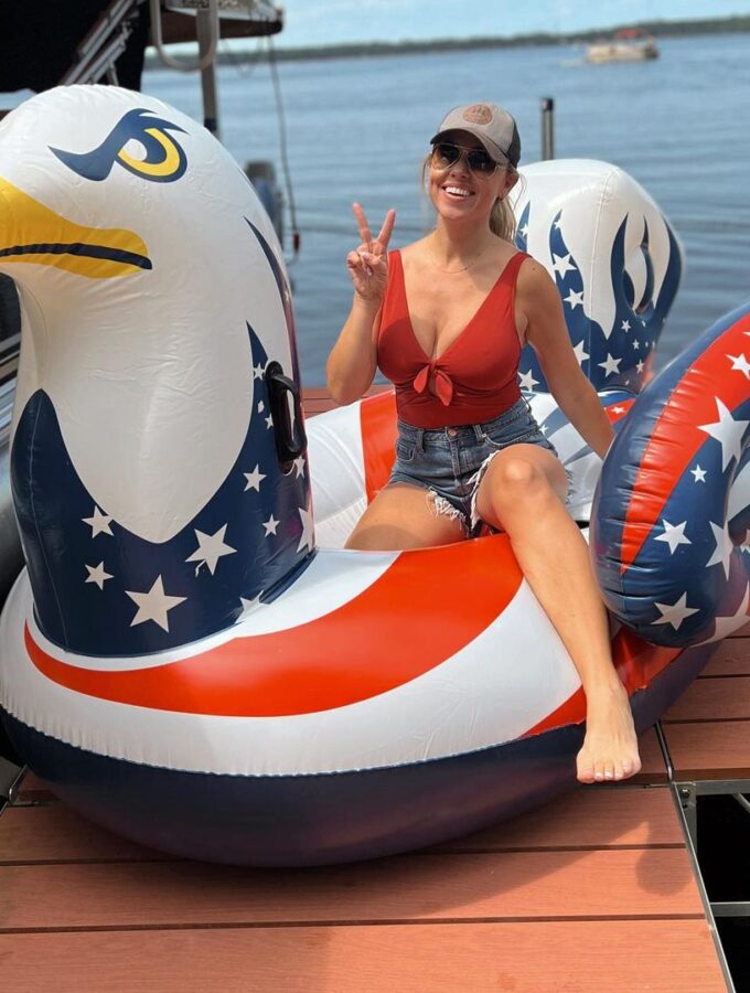 Jessica Hall sitting on a pool float shaped like an eagle with red, white, and blue wings.