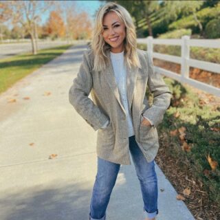 Jessica Hall standing by a white fence wearing jeans and a blazer.