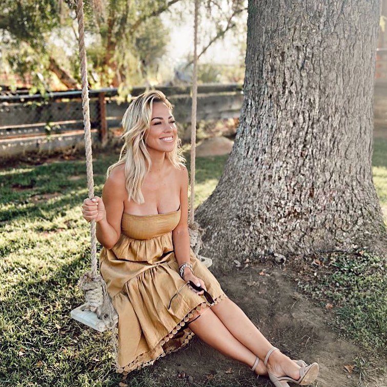 Jessica Hall wearing a tan strapless dress and sitting on a tree swing.