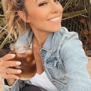 Jessica Hall wearing a denim jacket and holding a cocktail.