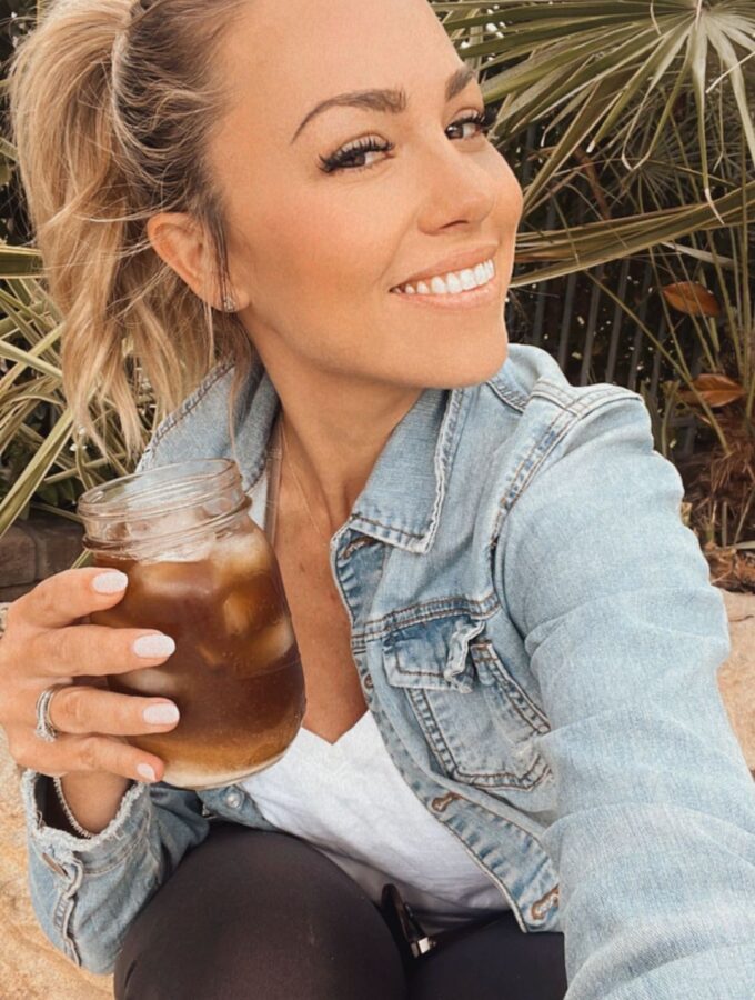 Jessica Hall wearing a denim jacket and holding a cocktail.