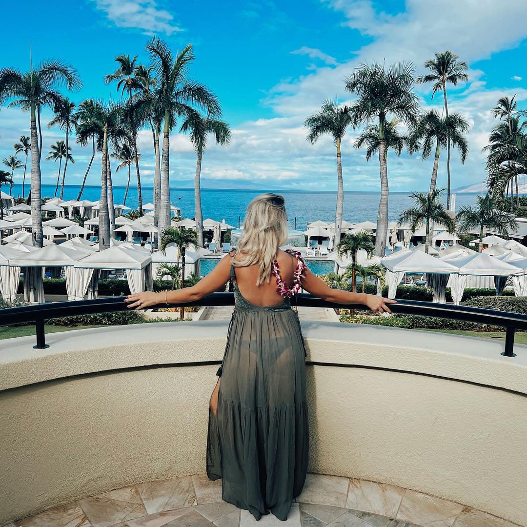 Woman standing on a balcony overlooking boats and the sea.